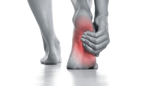 woman holding her painful foot on white woman holding her painful foot on white background
